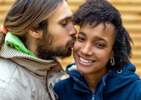 guy with an african  girl in love hugging  in autumn park walk at sunsetの写真素材