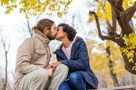 guy with an african girl in love in autumn park walk at sunsetの写真素材