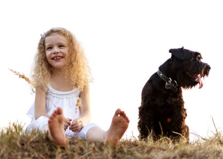 little girl with a dog plays in the park at sunsetの写真素材