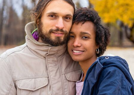 guy with an african american girl in love in autumn park walk at sunsetの写真素材