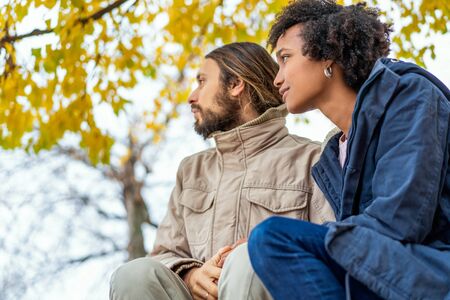 guy with an african girl in love in autumn park walk at sunsetの写真素材