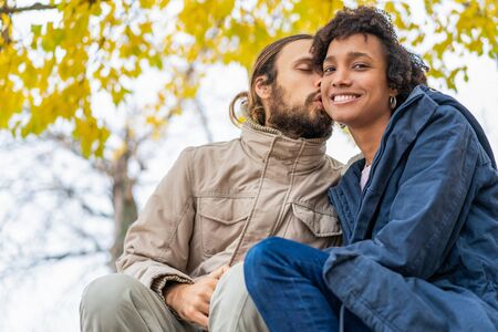 guy with an african girl in love in autumn park walk at sunsetの写真素材