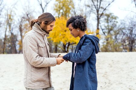 guy with an african american girl in love in autumn park makes her an offer to get marriedの写真素材