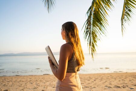freelancer girl with a computer among tropical palm trees work on the islandの写真素材