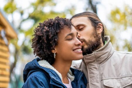 guy with an african  girl in love hugging  in autumn park walk at sunset
