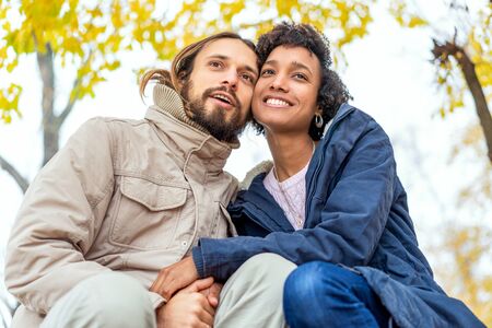 guy with an african girl in love in autumn park walk at sunsetの写真素材