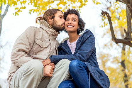 guy with an african girl in love in autumn park walk at sunsetの写真素材