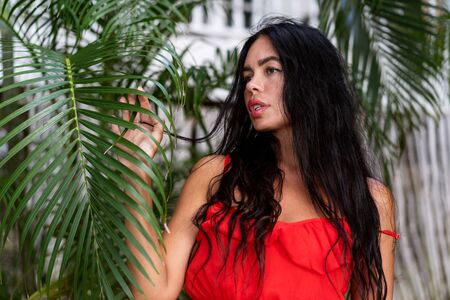 girl in a red dress among tropical palm trees in Thailand at sunsetの写真素材