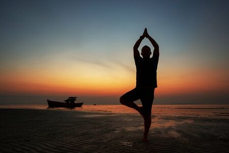 guy at sunset on the island practices yoga, silhouetteの写真素材
