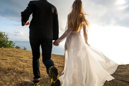 couple in love in the mountains in wedding dresses at sunsetの写真素材