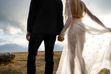 couple in love in the mountains in wedding dresses at sunset