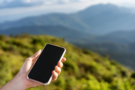 guy holding a phone in the mountains at sunsetの写真素材