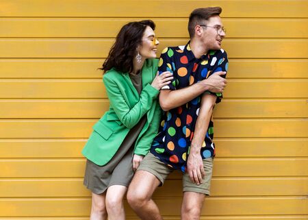 Young fashionable couple on yellow backgroundの写真素材