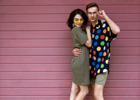 Young fashionable couple on pink backgroundの写真素材