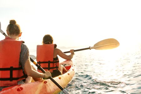 Couple kayaking together. Beautiful young couple kayaking on lake together and smiling at sunsetの写真素材