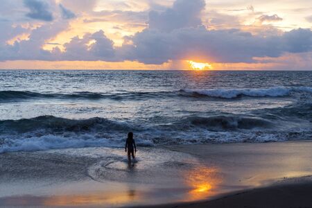 little boy near the ocean at sunsetの写真素材