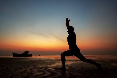 guy at sunset on the island practices yoga, silhouetteの写真素材