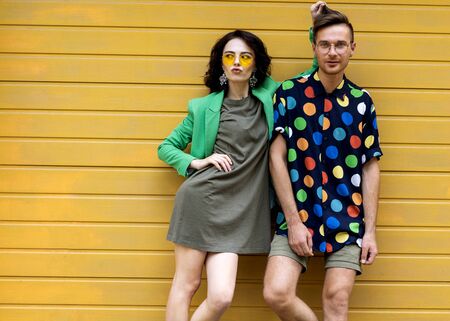 Young fashionable couple on yellow backgroundの写真素材
