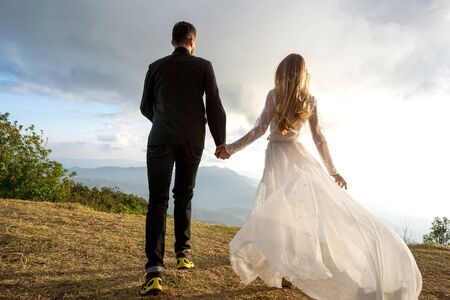 couple in love in the mountains in wedding dresses at sunsetの写真素材