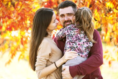 family with daughter walks in autumn parkの写真素材