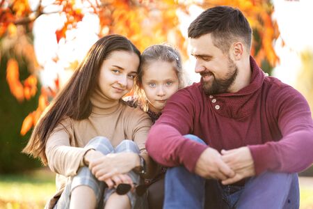 family with daughter walks in autumn parkの写真素材