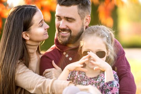 family with daughter walks in autumn parkの写真素材
