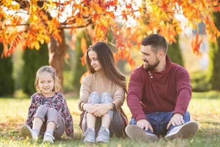 family with daughter walks in autumn parkの写真素材