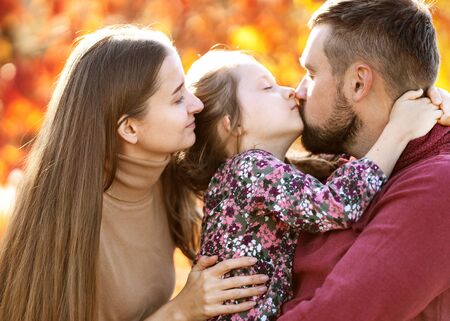 family with daughter walks in autumn parkの写真素材