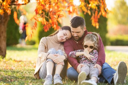 family with daughter walks in autumn parkの写真素材