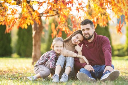 family with daughter walks in autumn parkの写真素材
