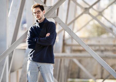 fashion guy stands posing near a white wall in sunglassesの写真素材