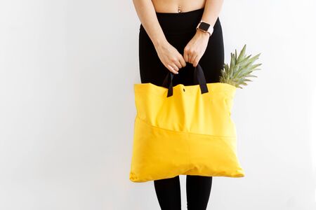 girl with a shopping bag in yellow hands with products. Take away, fitness food.の写真素材