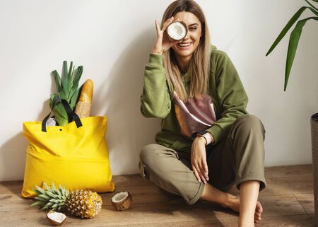 Beautiful fashion girl does shopping with herself, food delivery, take away food.  Girl sitting at home with a bag of foodの写真素材