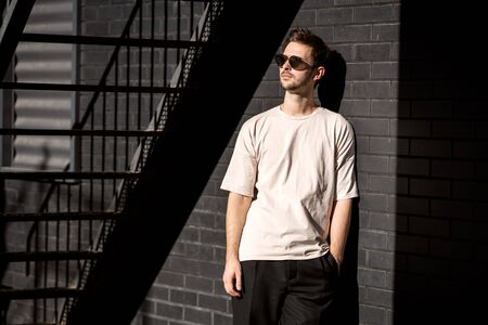 fashion guy posing in sunglasses against a black urban backgroundの写真素材