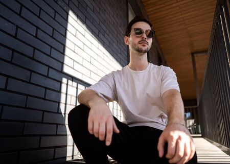 fashion guy posing in sunglasses against a black urban backgroundの写真素材