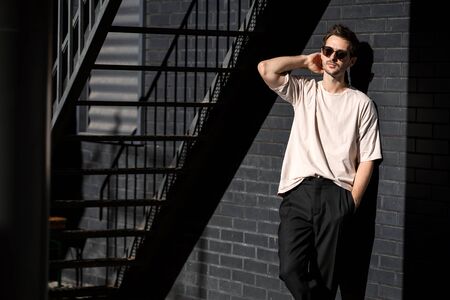 fashion guy posing in sunglasses against a black urban backgroundの写真素材