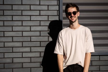 fashion guy posing in sunglasses against a black urban backgroundの写真素材