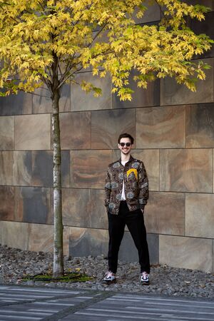 fashion guy posing in sunglasses against a black urban background in autumnの写真素材