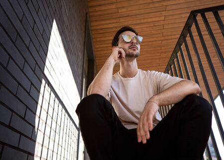 fashion guy posing in sunglasses against a black urban backgroundの写真素材