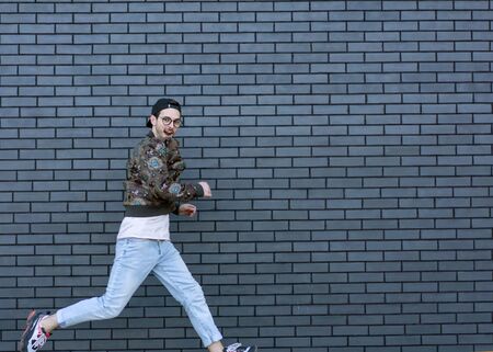 fashion guy runs and poses brick black urban backgroundの写真素材