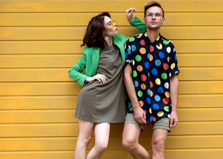 Young fashionable couple on yellow backgroundの写真素材