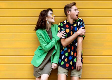Young fashionable couple on yellow backgroundの写真素材