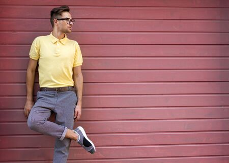 fashion guy standing in yellow clothes and glasses near the pink wallの写真素材