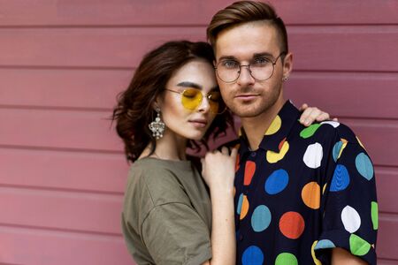 Young fashionable couple on pink backgroundの写真素材
