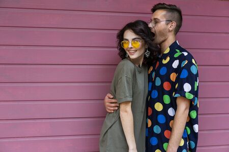 Young fashionable couple on pink backgroundの写真素材