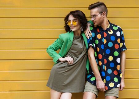 Young fashionable couple on yellow backgroundの写真素材