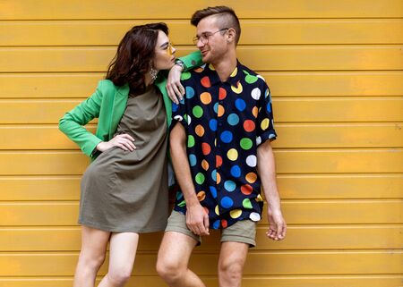 Young fashionable couple on yellow backgroundの写真素材
