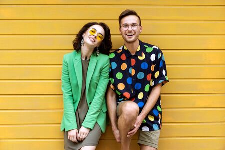 Young fashionable couple on yellow backgroundの写真素材