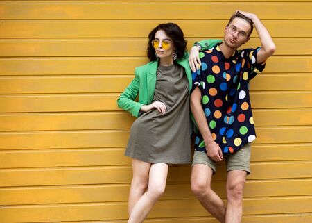Young fashionable couple on yellow backgroundの写真素材