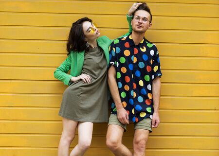 Young fashionable couple on yellow backgroundの写真素材